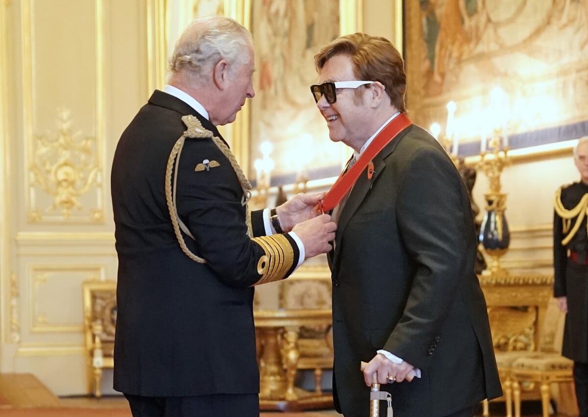 Sir Elton John, a la derecha, es nombrado miembro de la Orden de los Compañeros de Honor por el príncipe Carlos