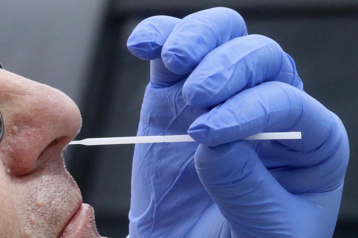 A nurse uses a swab to perform a coronavirus test.