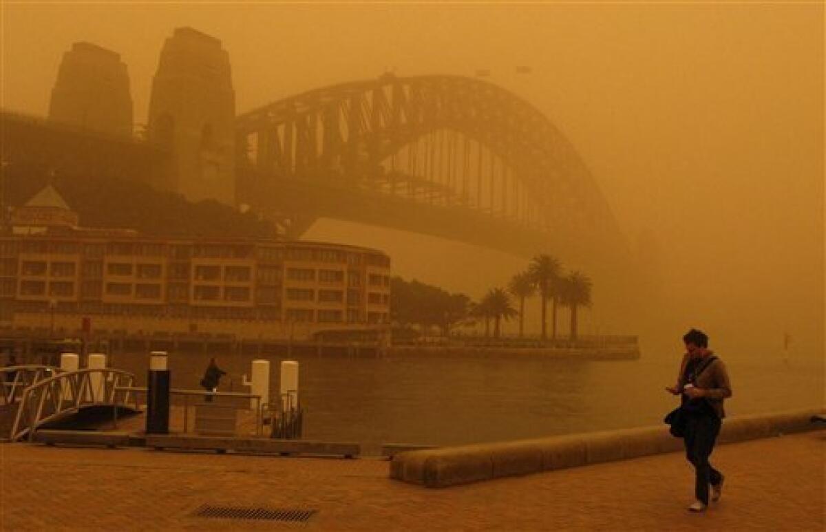 A man walks to work past an almost unseen Sydney Harbour Bridge during a dust storm Wednesday, Sept. 23, 2009 in Sydney, Australia.Flights are diverted and ferries canceled as a blanket of red dust shrouded most of Sydney after the weather system moved in from central Australia.(AP Photo/Rob Griffith)