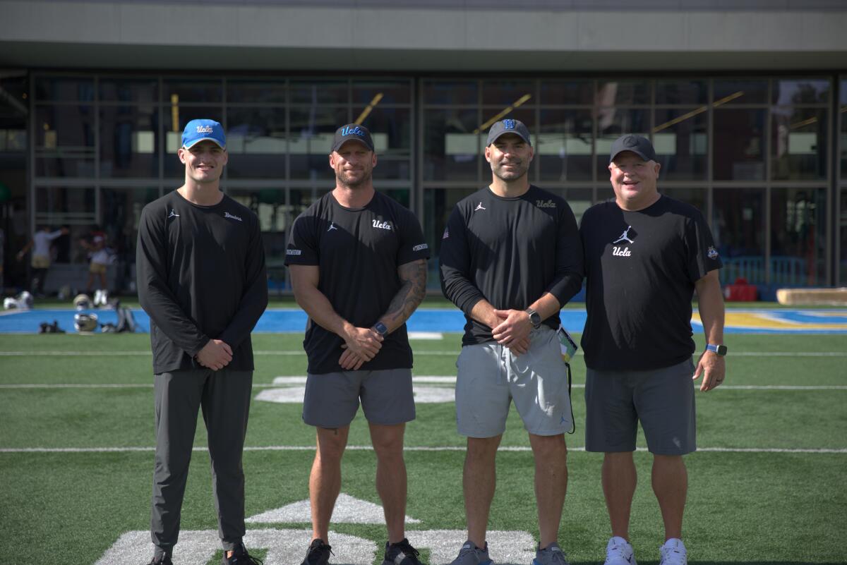 Anthony Goliver, Mike Poppa, Bryce McDonald and Chip Kelly stand together on the UCLA practice field.