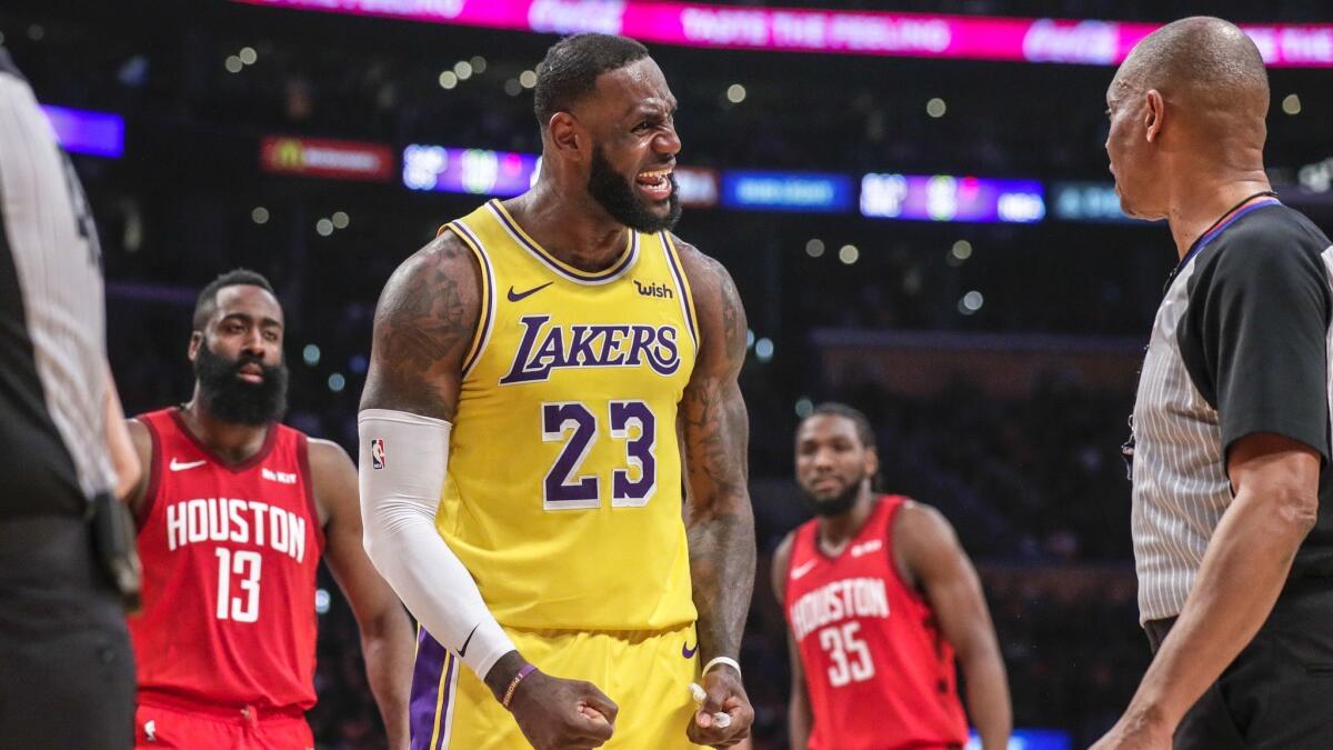 Lakers forward LeBron James debates with referee Michael Smith over a call as Rockets' James Harden watches.