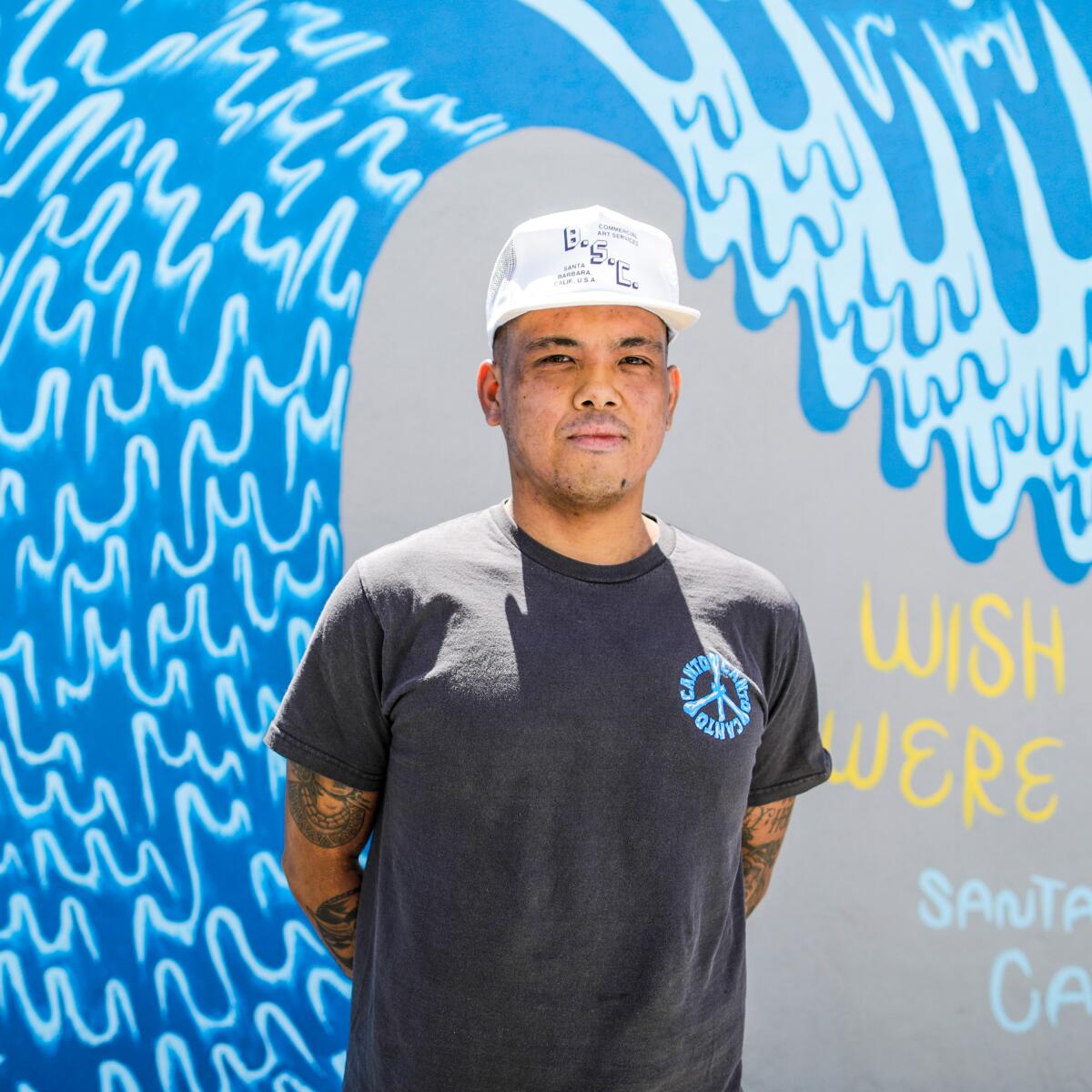 Man standing in front of a mural showing a wave