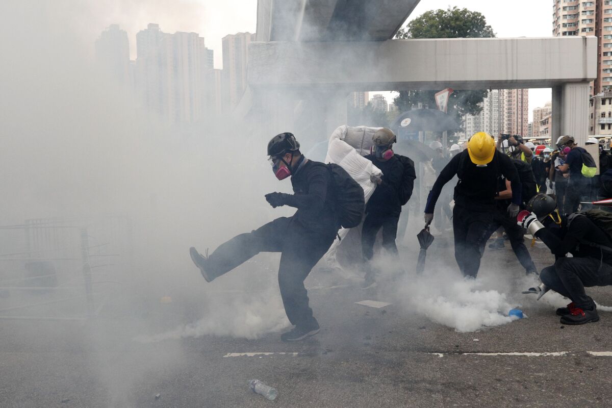 Protesters kick back tear-gas canisters as they clash with riot police Saturday in Hong Kong's Yuen Long district.