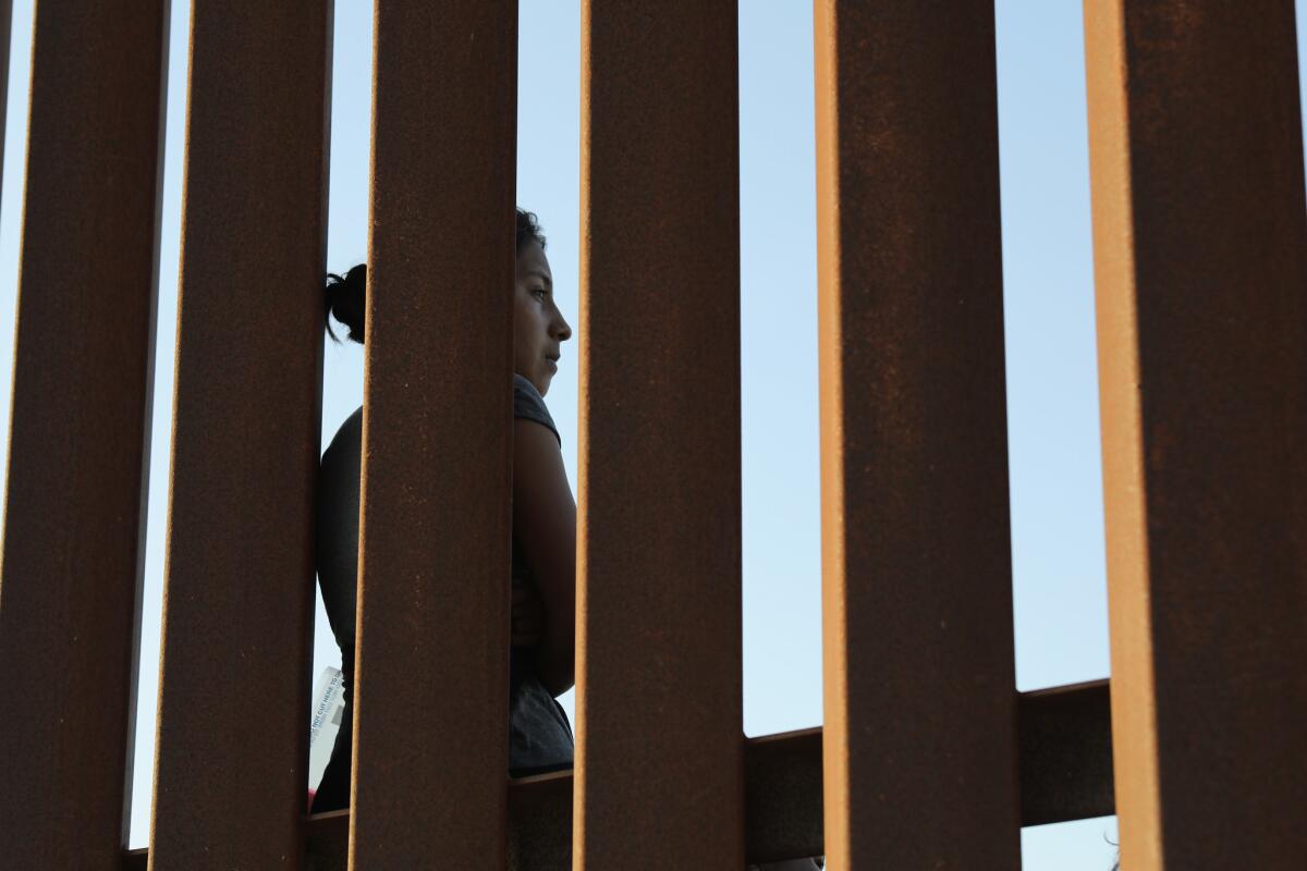 A Central American immigrant stands at the U.S.-Mexico border fence after crossing into Texas