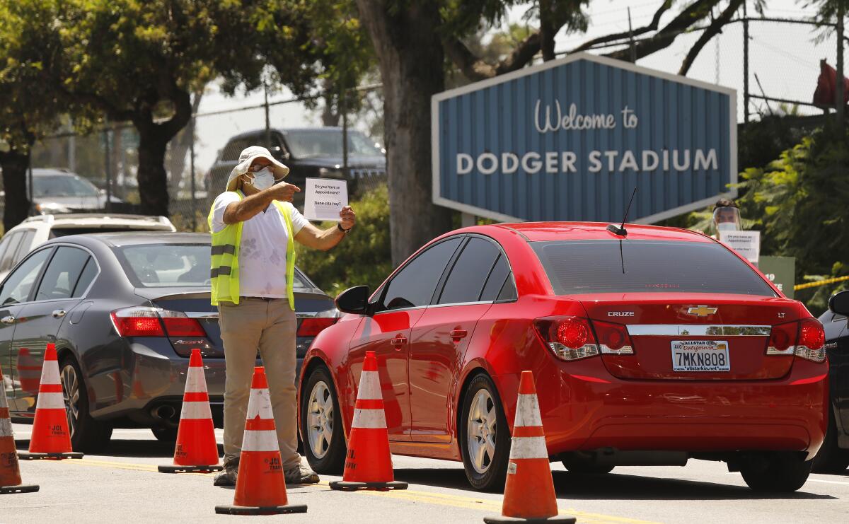 Workers confirm that drivers have an appointment for coronavirus testing that resumed at Dodger Stadium this week.