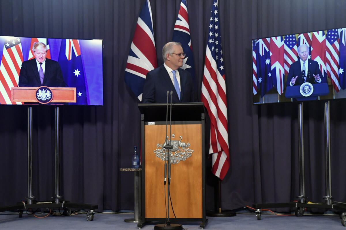 Australia's Prime Minister Scott Morrison, center, appears on stage with video links to Britain's Prime Minister Boris Johnson, left, and U.S. President Joe Biden at a joint press conference at Parliament House in Canberra, Thursday, Sept. 16, 2021. The leaders are announcing a security alliance that will allow for greater sharing of defense capabilities — including helping equip Australia with nuclear-powered submarines. (Mick Tsikas/AAP Image via AP)