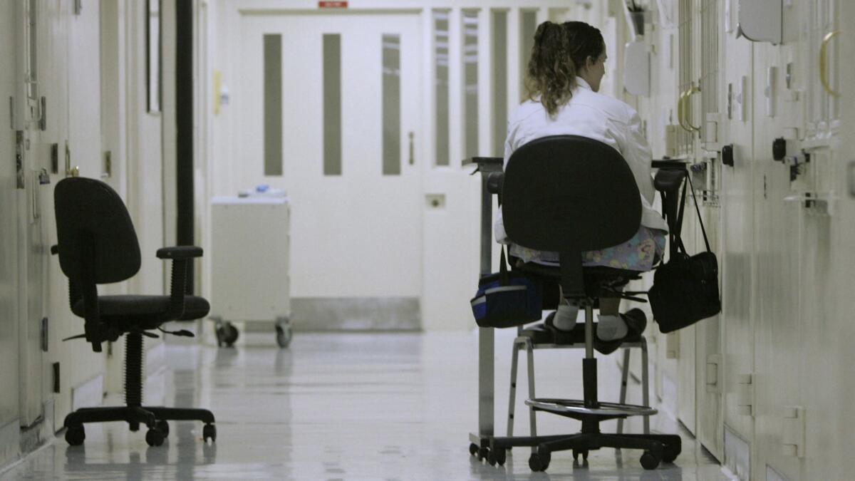 In this March 30, 2008, file photo, a medical worker sits outside an isolation cell containing an inmate who authorities fear might attempt suicide at California State Prison Sacramento in Folsom, Calif.