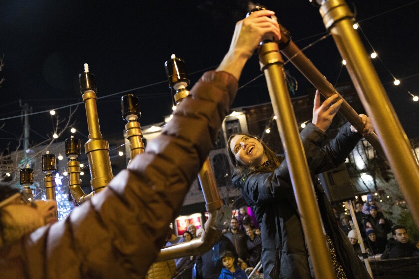 Rabbanit Dasi Fruchter, of the South Philadelphia Shtiebel, lights a menorah during a public Hanukkah celebration and menorah lighting ceremony in South Philadelphia on Sunday, Dec. 5, 2021. Fruchter is one of about a half-dozen ordained women who serve Modern Orthodox synagogues across the U.S. and one of even fewer who serve as top spiritual leaders. (AP Photo/Ryan Collerd)