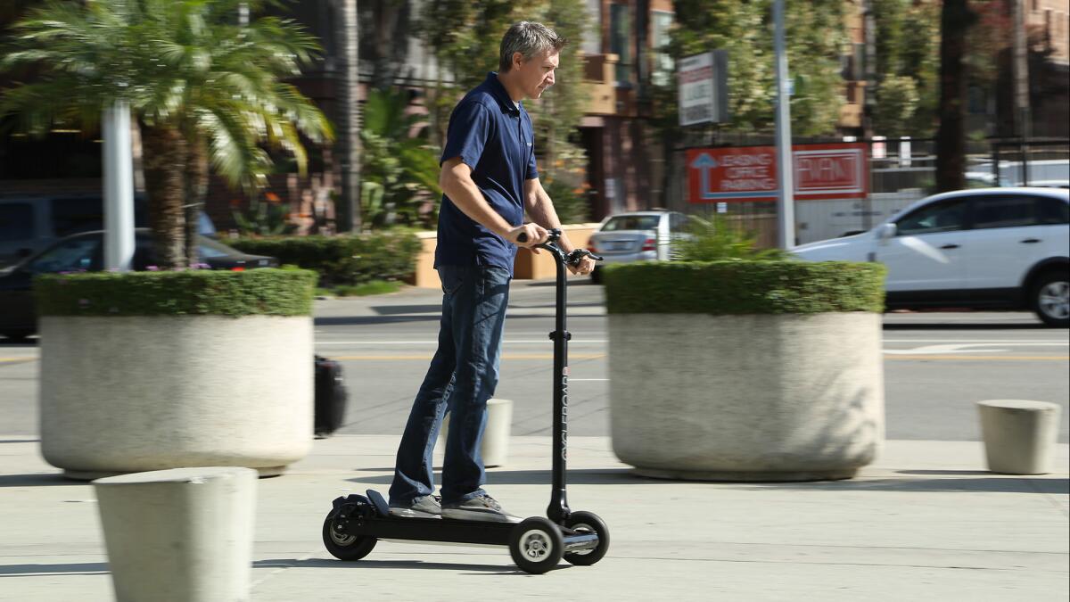 Phil LaBonty demonstrates his company's three-wheeled CycleBoard at the L.A. Auto Show.