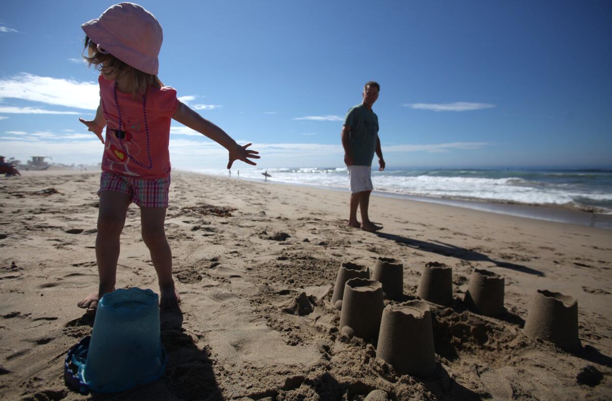Haley Nelson, 3, and her father, Ryan Nelson, of Whittier, play in the sand at Huntington State Beach during Labor Day weekend in 2013. U.S. travelers are expected to spend $13.5 billion during this holiday weekend.