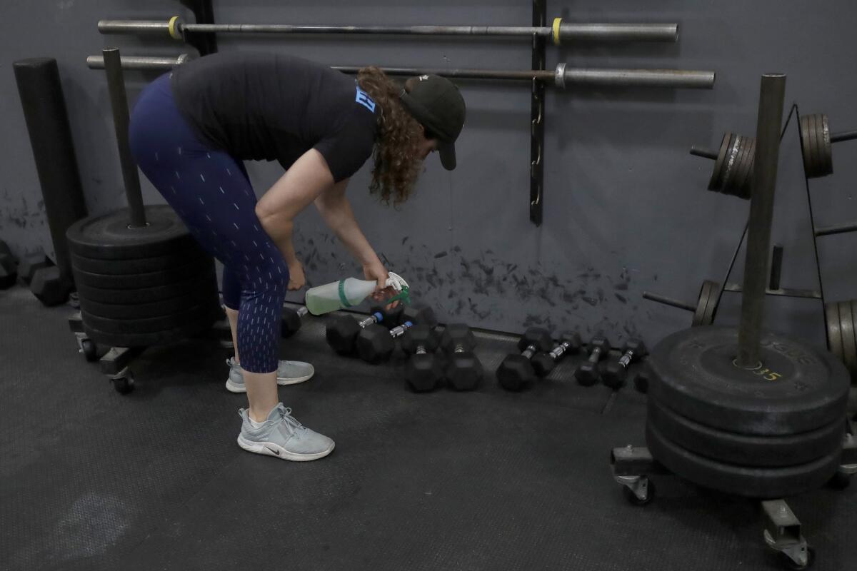 Alexis Garrod, CrossFit Potrero Hill partner and head coach, cleans off equipment in an empty gym in San Francisco. 