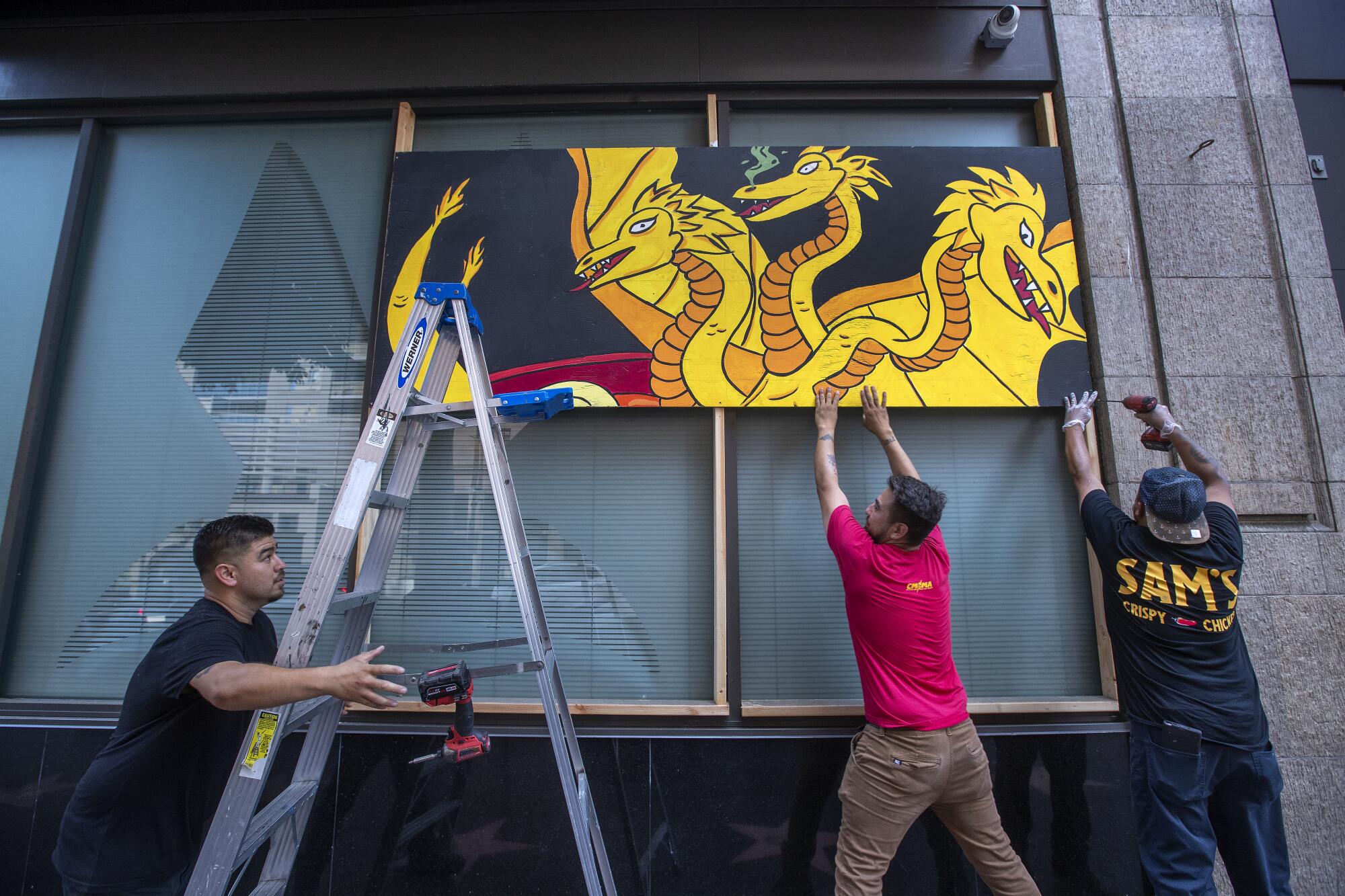 Workers take down the last board that protected the windows at Katsuya restaurant