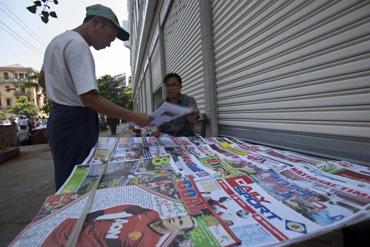 A man picks up a local weekly journal as a street vendor displays newspapers and journals for sale in Yangon, Myanmar, in March 2013.
