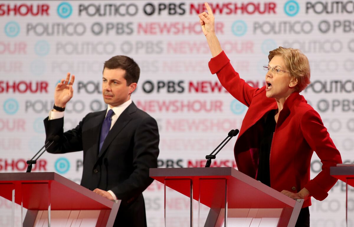 Candidates Pete Buttigieg and Elizabeth Warren raise their hands at Thursday's Democratic presidential primary debate in Los Angeles.