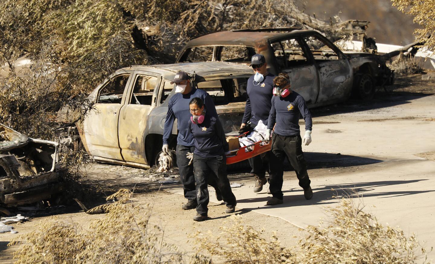 Los Angeles County coroner's workers recover a body at a burned home in the 32000 block of Lobo Canyon Road in Agoura Hills on Wednesday.