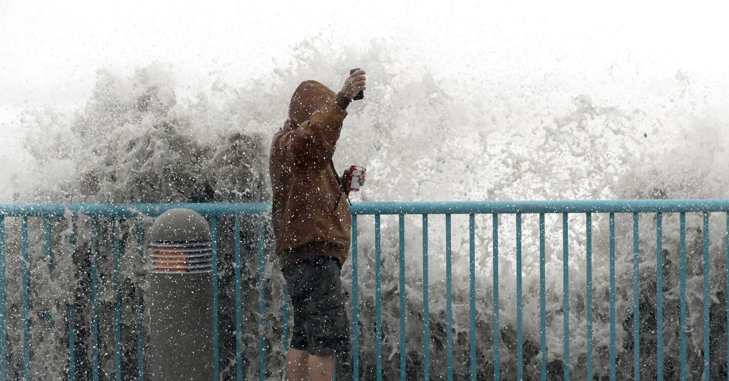 Brian Johns is hit by a wave as he tries to film the effects of Hurricane Matthew with his cellphone, on Oct. 7, 2016, in Daytona Beach, Fla.