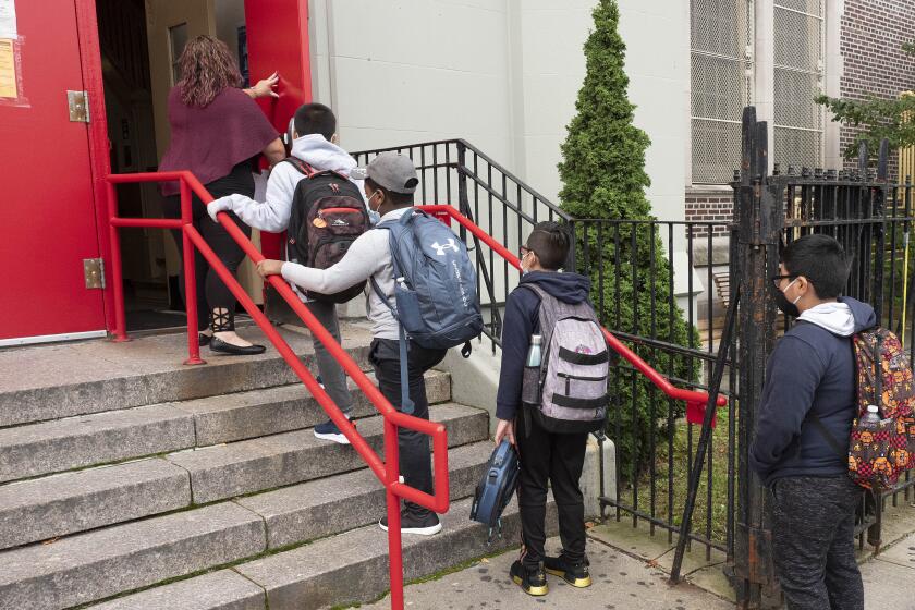 Una profesora conduce a sus estudiantes hacia el interior de una escuela primaria de Brooklyn, Nueva York, el martes 29 de septiembre de 2020. (AP Foto/Mark Lennihan)