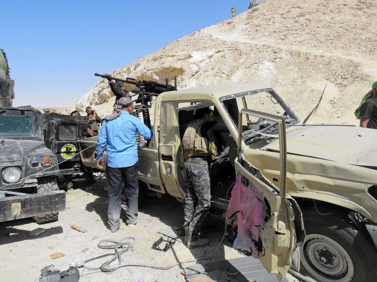Iraqi security forces and Sunni tribesmen inspect damaged vehicles after an attack this week on a military post in Anbar province, in western Iraq.
