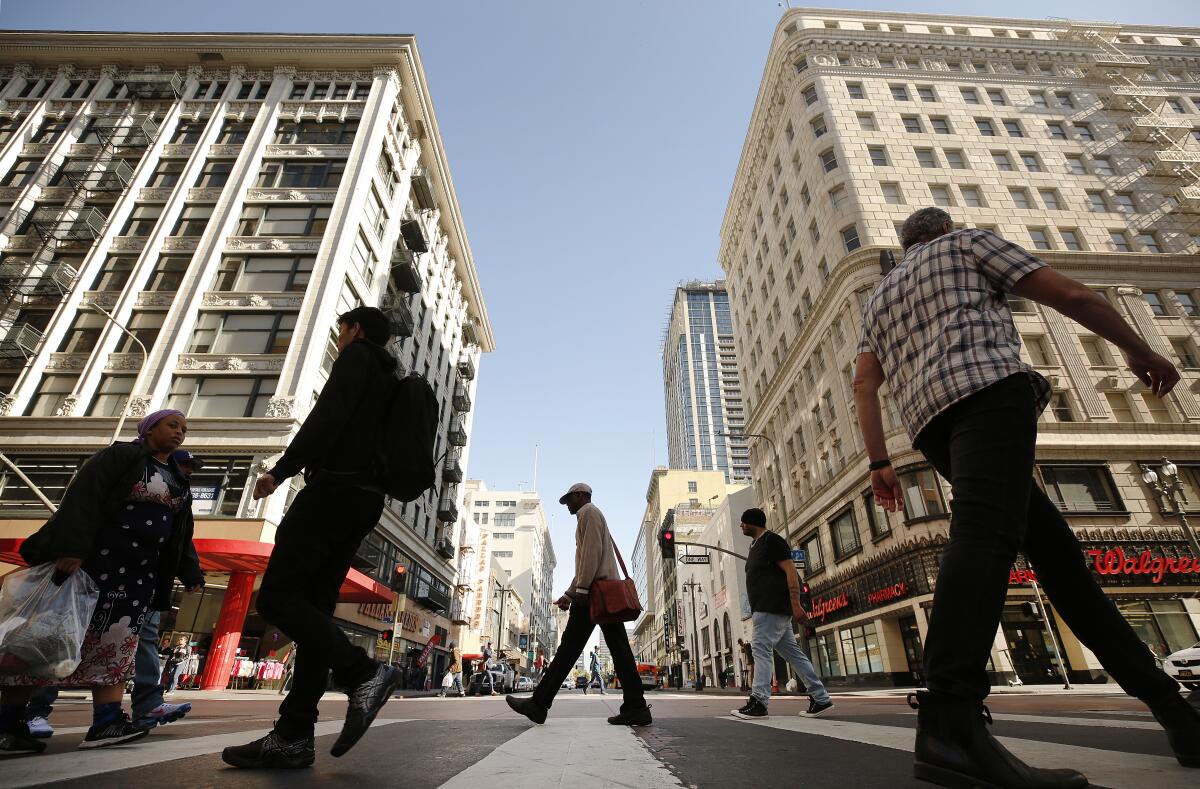 Pedestrians cross Broadway at 5th Street.