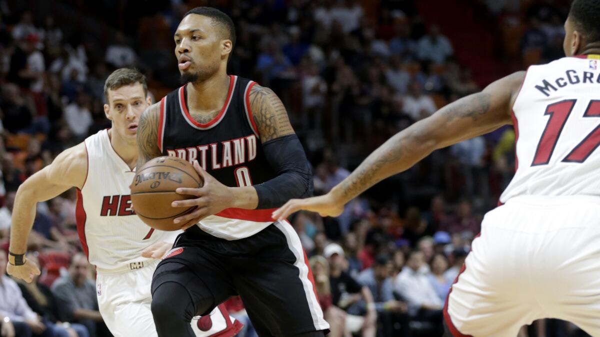 Trail Blazers point guard Damian Lillard (0) drives to the basket between the Heat's Goran Dragic, left, and Rodney McGruder during the first half.