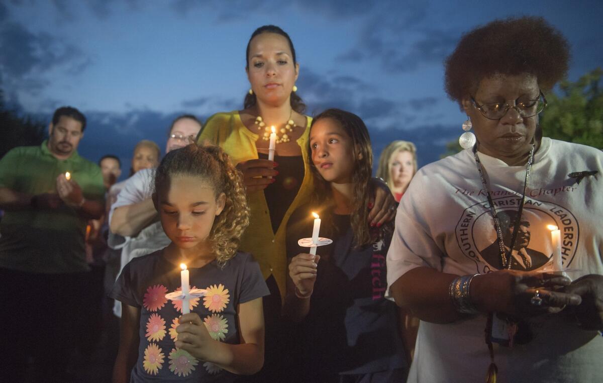 From left, Amora DeVries, 7, Afira DeVries, Eva DeVries, 9, and Brenda Keeling of Roanoke show their support for two slain TV journalists at a candlelight vigil in front of the studios of WDBJ-TV in Roanoke, Va.