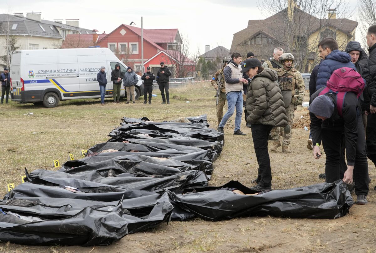 Ukrainian Prosecutor General Iryna Venediktova, center, looks at the exhumed bodies of civilians killed during the Russian occupation in Bucha, on the outskirts of Kyiv, Ukraine, Friday, April 8, 2022. An international organization formed to identify the dead and missing from the 1990s Balkan conflicts is preparing to send a team of forensics experts to Ukraine as the death toll mounts more than six weeks into the war caused by Russia's invasion. (AP Photo/Efrem Lukatsky)