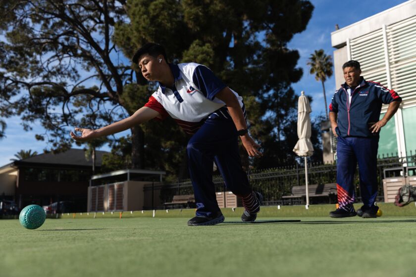 Angel Gomez, 17, releases his bowl as his father, Javier Gomez, who is also his coach, watches during practice at the Coronado Lawn Bowling Club on Monday, Nov. 21, 2022. Angel will be competing as the only American in the International Indoor Bowls Council Junior Championship in Ireland.