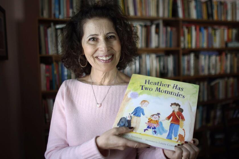 In this Wednesday, March 11, 2015 photo, author Leslea Newman, of Holyoke, Mass., displays a copy of her book "Heather Has Two Mommies," in Holyoke. Newman, who wrote the original version of "Heather Has Two Mommies," 25 years ago, about a little girl named Heather and her two happy mommies, has updated the book with fresh illustrations from a new artist. (AP Photo/Steven Senne)