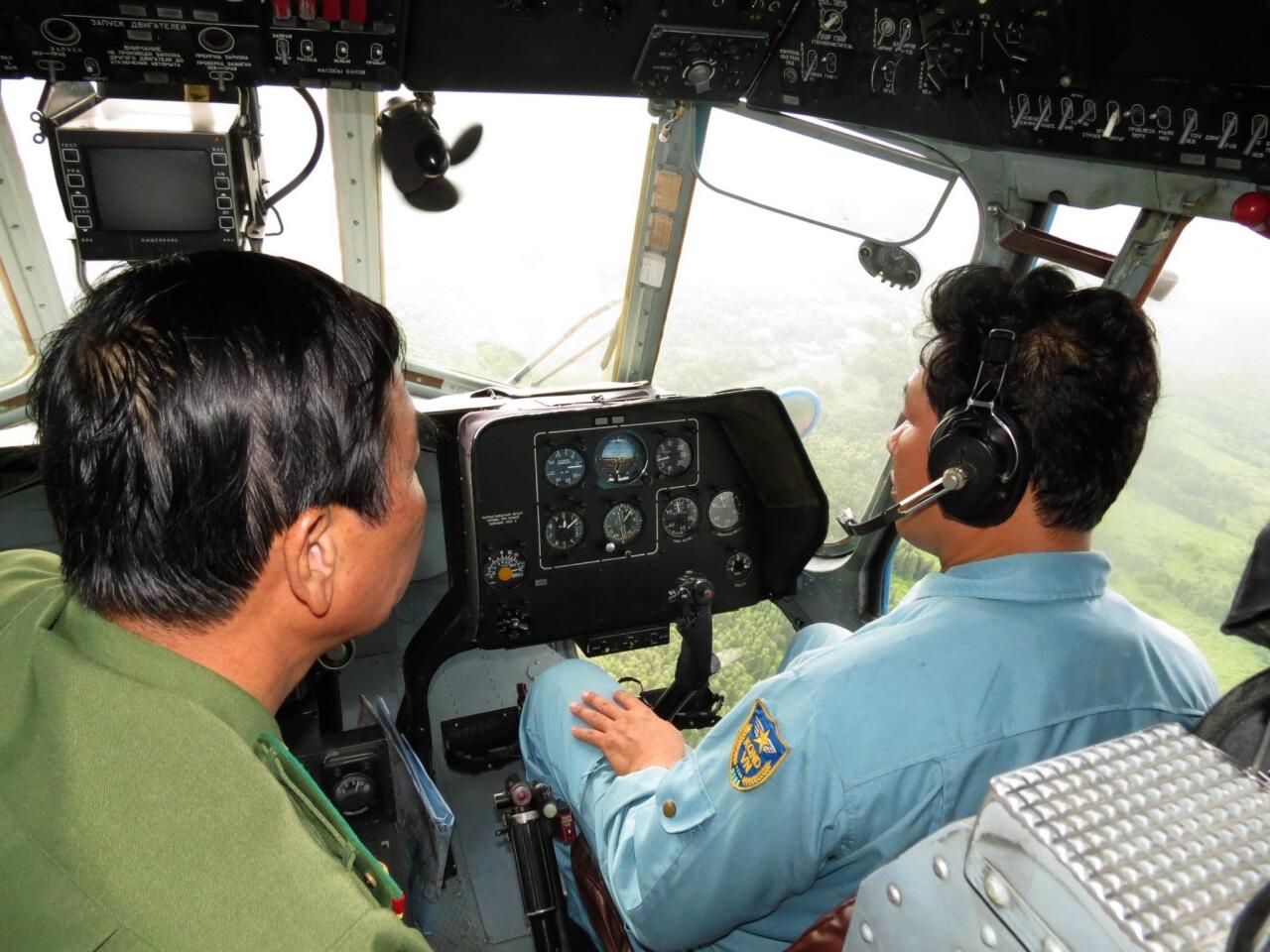 This picture taken aboard a Vietnam Air Force Russian-made MI-17 helicopter shows a crew member (R) and a coast guard officer during a search operation for the missing Malaysia Airlines flight MH370 plane over the U Minh jungle in southern province of Ca Mau.