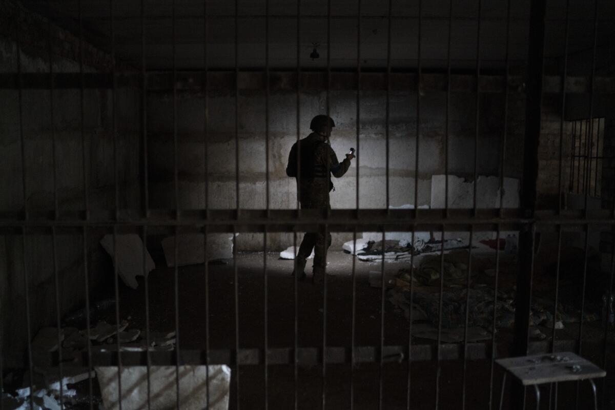 A Ukrainian service member is silhouetted in a dark basement.