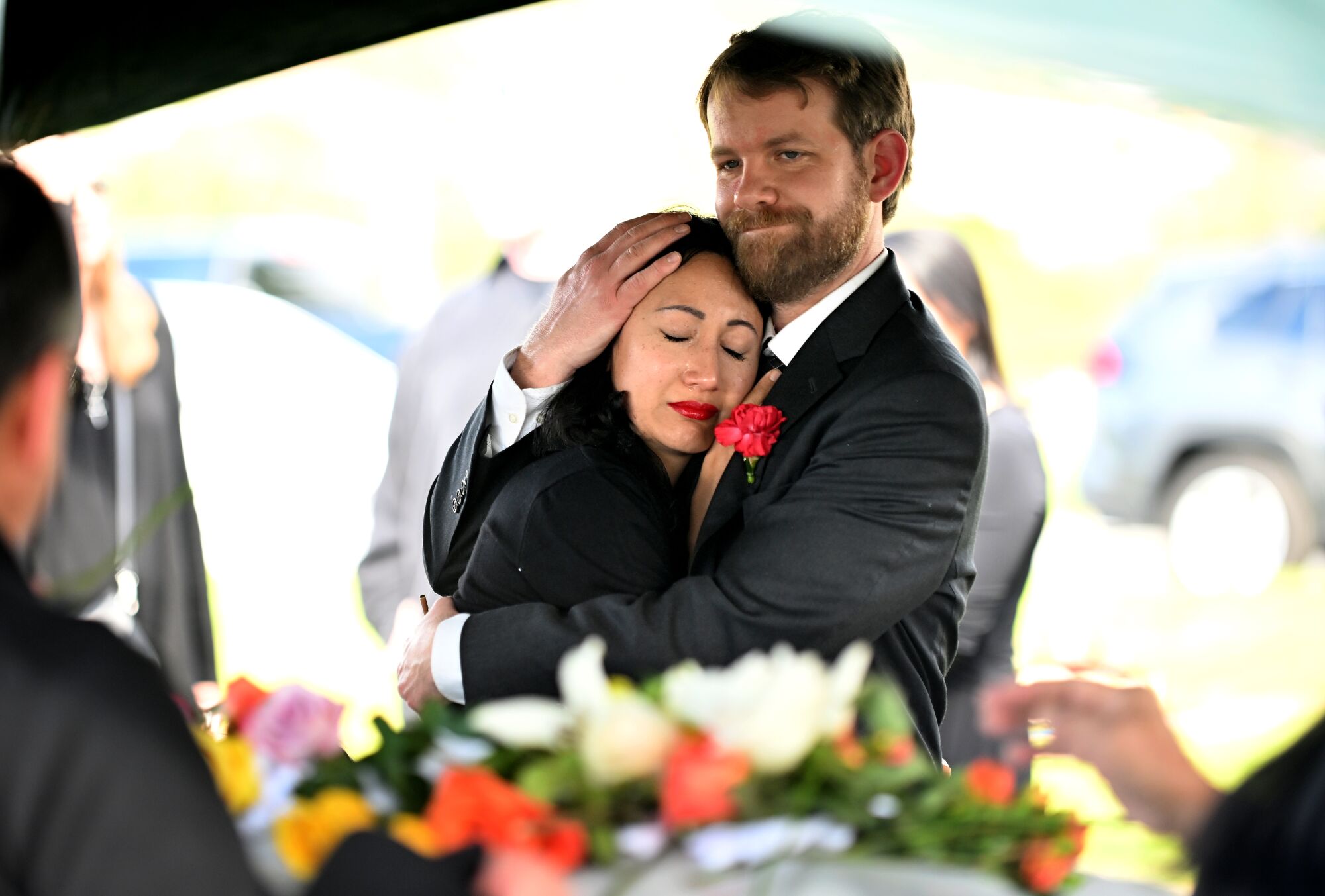 Kristenne Reidy is held by her husband Skyler near the casket