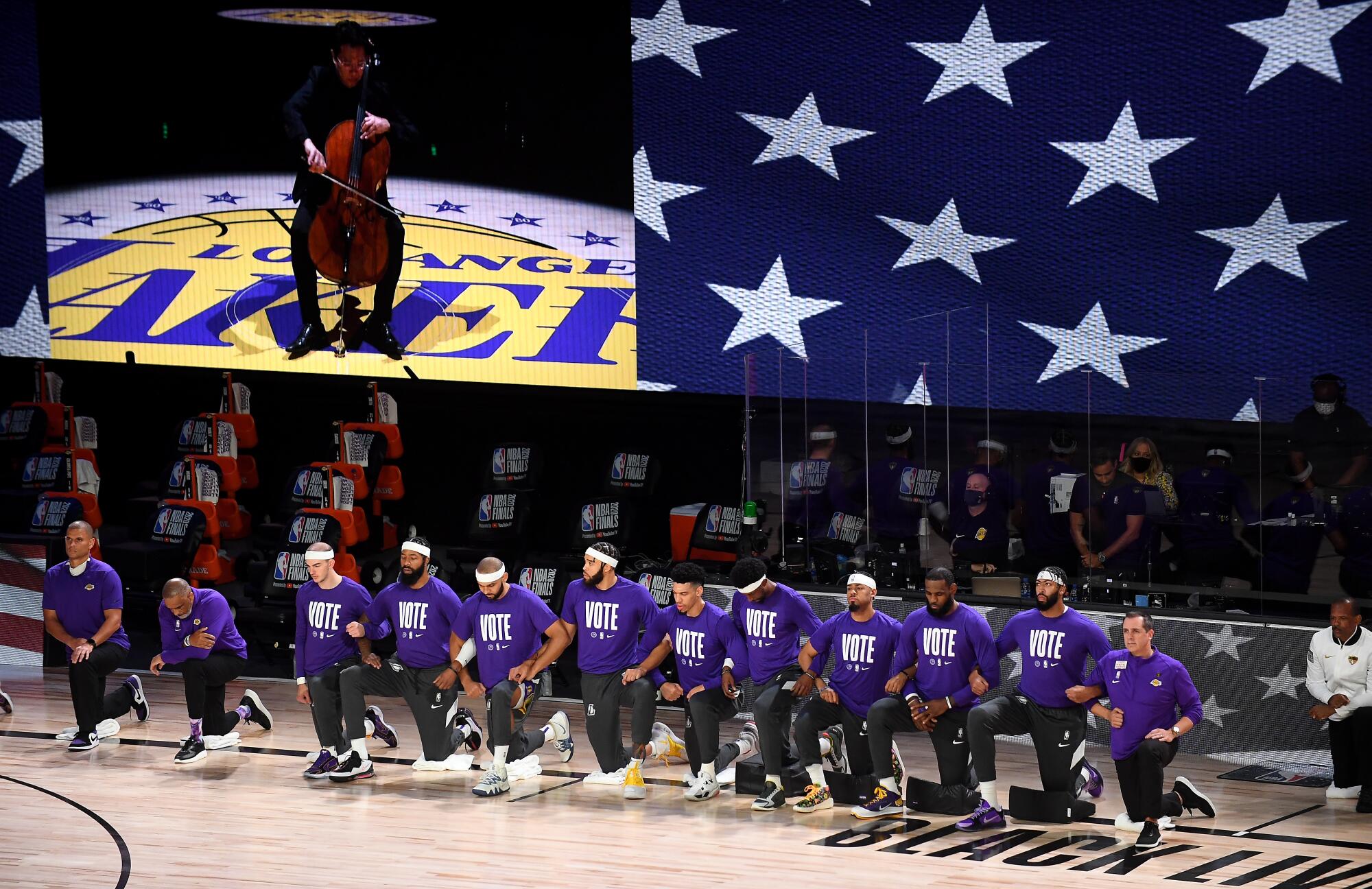 Lakers players and coaches lock arms as they listen to L.A. Philharmonic celloist Ben Hong play the national anthem.