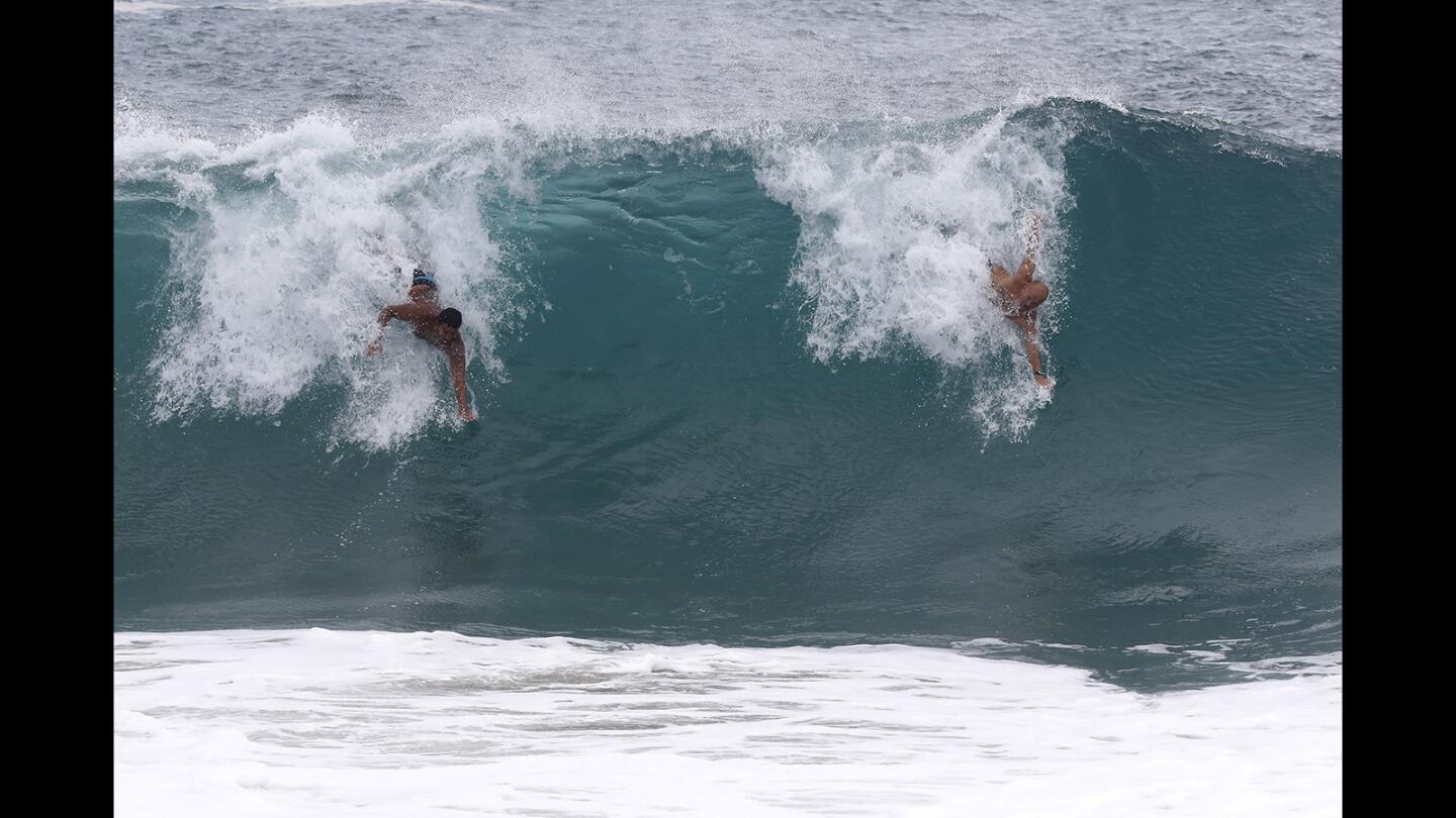 Bodysurfers share a wave Monday at the Wedge in Newport Beach, where waves were in the 8- to 10-foot range because of swells from Tropical Storm Rosa.