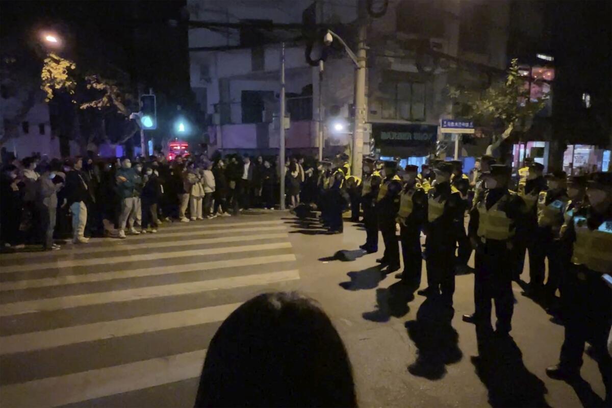 Chinese police officers block access to a site where protesters had gathered on a street.
