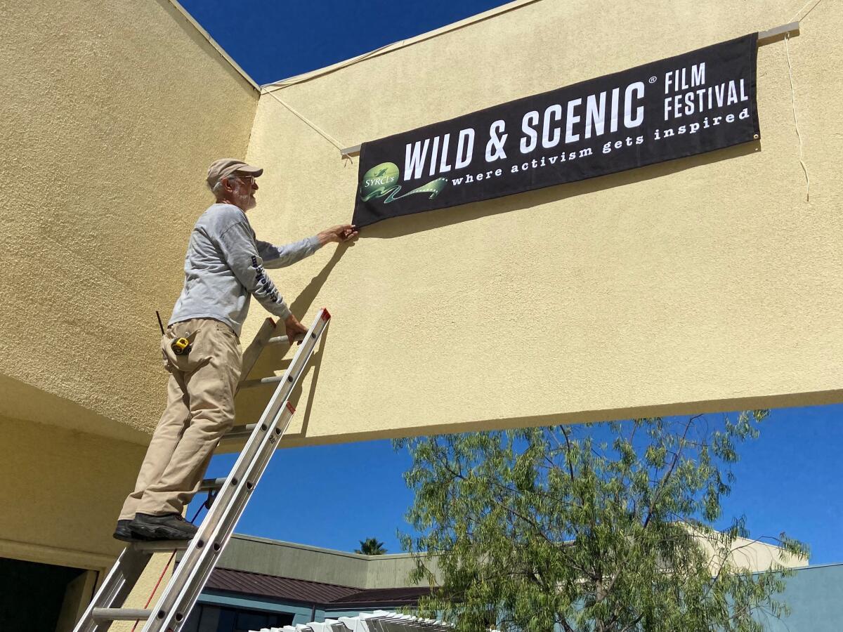 Craig Spery hangs a banner Wednesday for a film festival coming to Orange Coast Unitarian Universalist Church on Saturday.