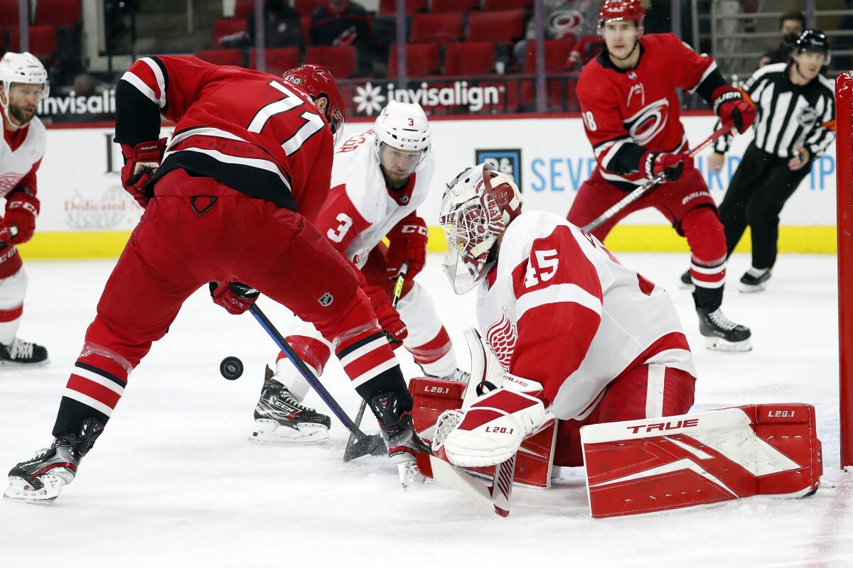 Carolina Hurricanes' Jesper Fast (71) tries to gather in the puck in front of Detroit Red Wings goaltender Jonathan Bernier (45) and Alex Biega (3) during the second period of an NHL hockey game in Raleigh, N.C., Monday, April 12, 2021. (AP Photo/Karl B DeBlaker)