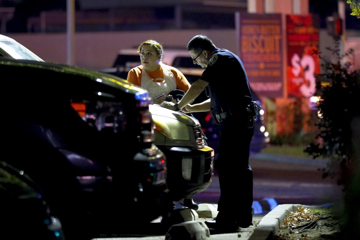 A San Diego police officer questions a witness after the shooting at a Church's Chicken restaurant in Otay Mesa.