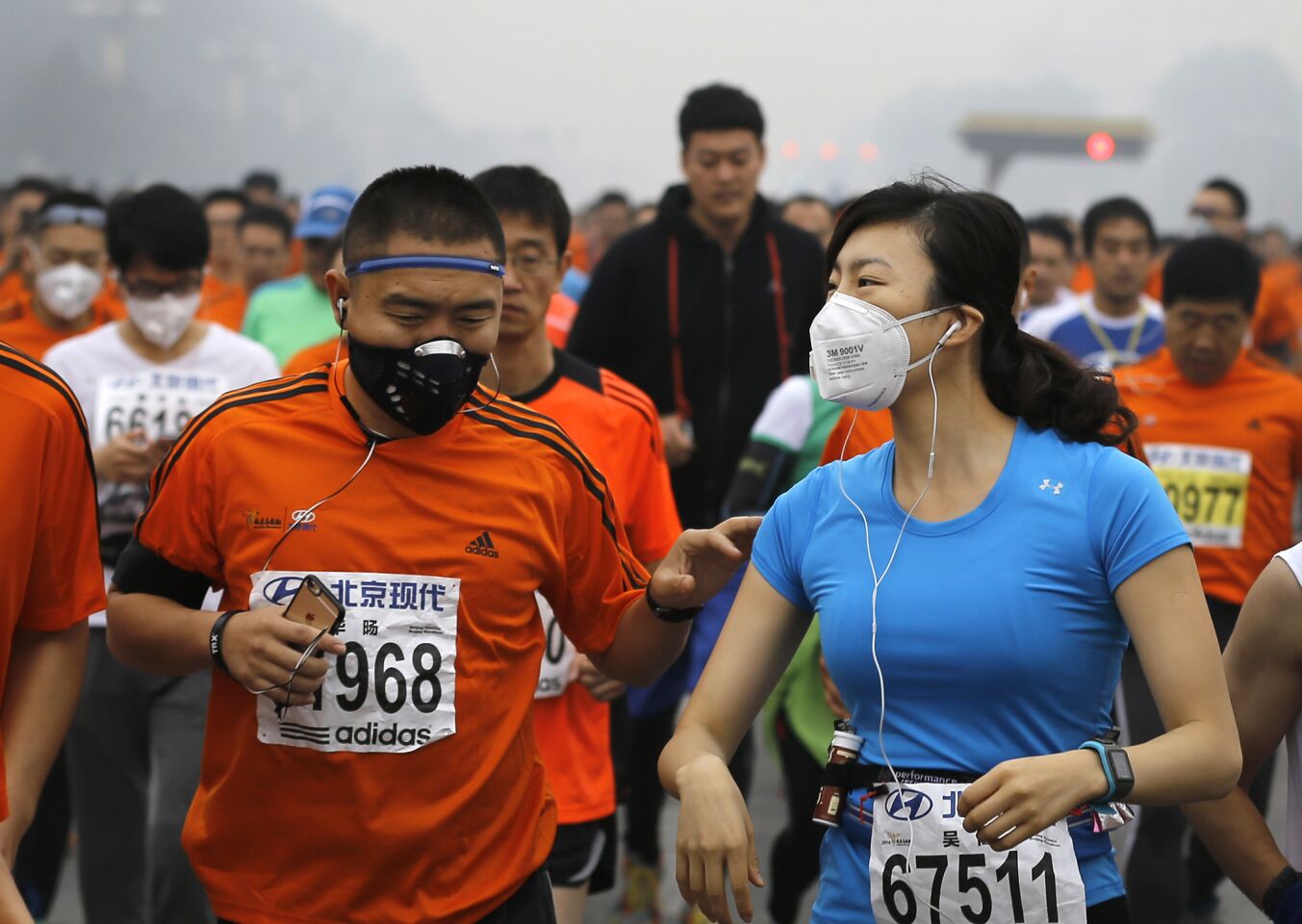 Runners wearing masks to protect themselves from pollutants jog past Chang'an Avenue near Tiananmen Square shrouded in haze while taking part in the 2014 Beijing International Marathon on Oct. 19.