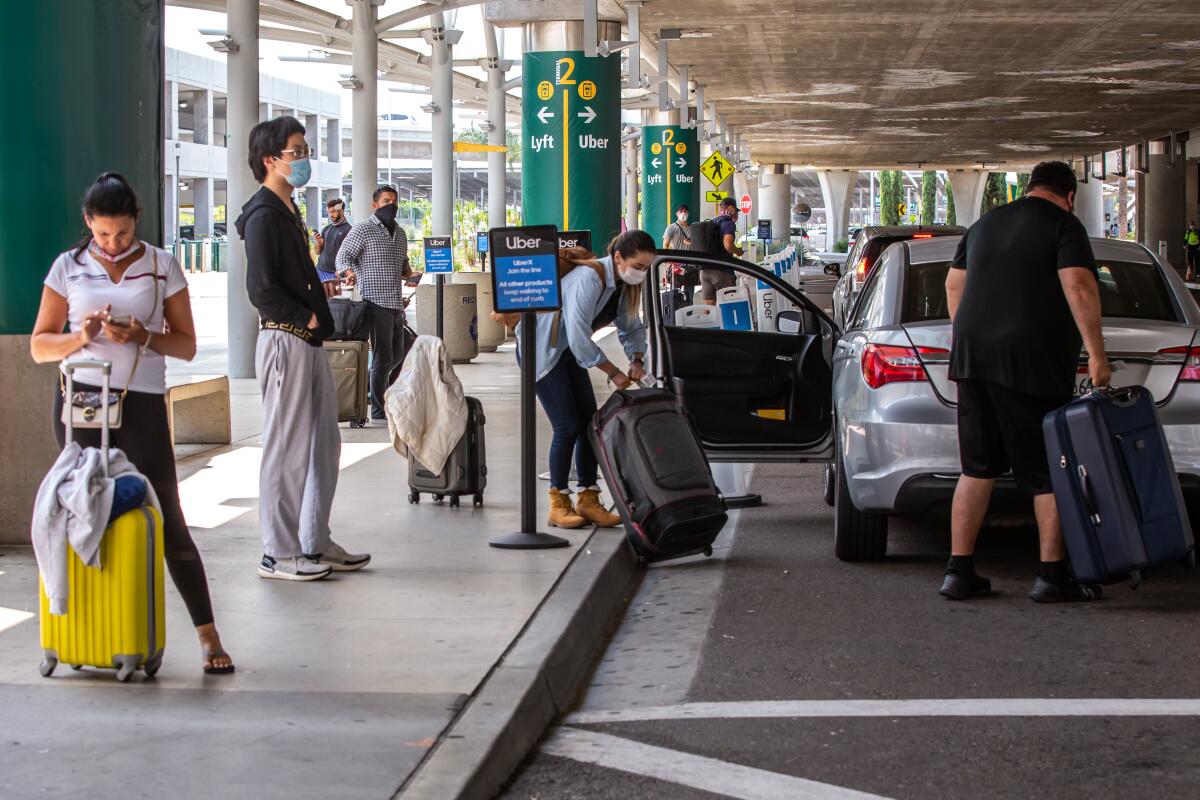 People wait for their ride share drivers to arrive at the San Diego Airport in this 2020 photo.