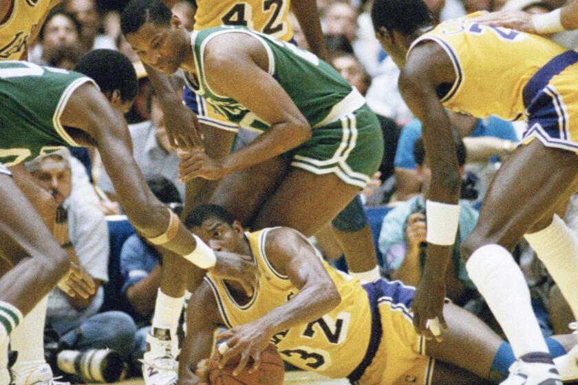 FILE - In this June 2, 1987, file photo, Los Angeles Lakers' Earvin "Magic" Johnson scrambles for the ball on the floor of The Forum during the NBA finals, in, Inglewood, Calif. Johnson is surrounded by unidentified Boston Celtics players. Kareem Abdul-Jabbar is at left. Itâs the rivalry against which all others are measured, the one essentially responsible for the modern NBA evolving from a fringe sport that put its championship series on tape delay to a global sensation built around the most recognizable athletes in American sports. (AP Photo/Mark Avery, File)