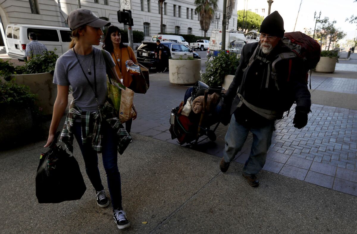 Homeless advocates Brooke Robie, left, and Tali Poran talk with a homeless man named John outside L.A. City Hall.