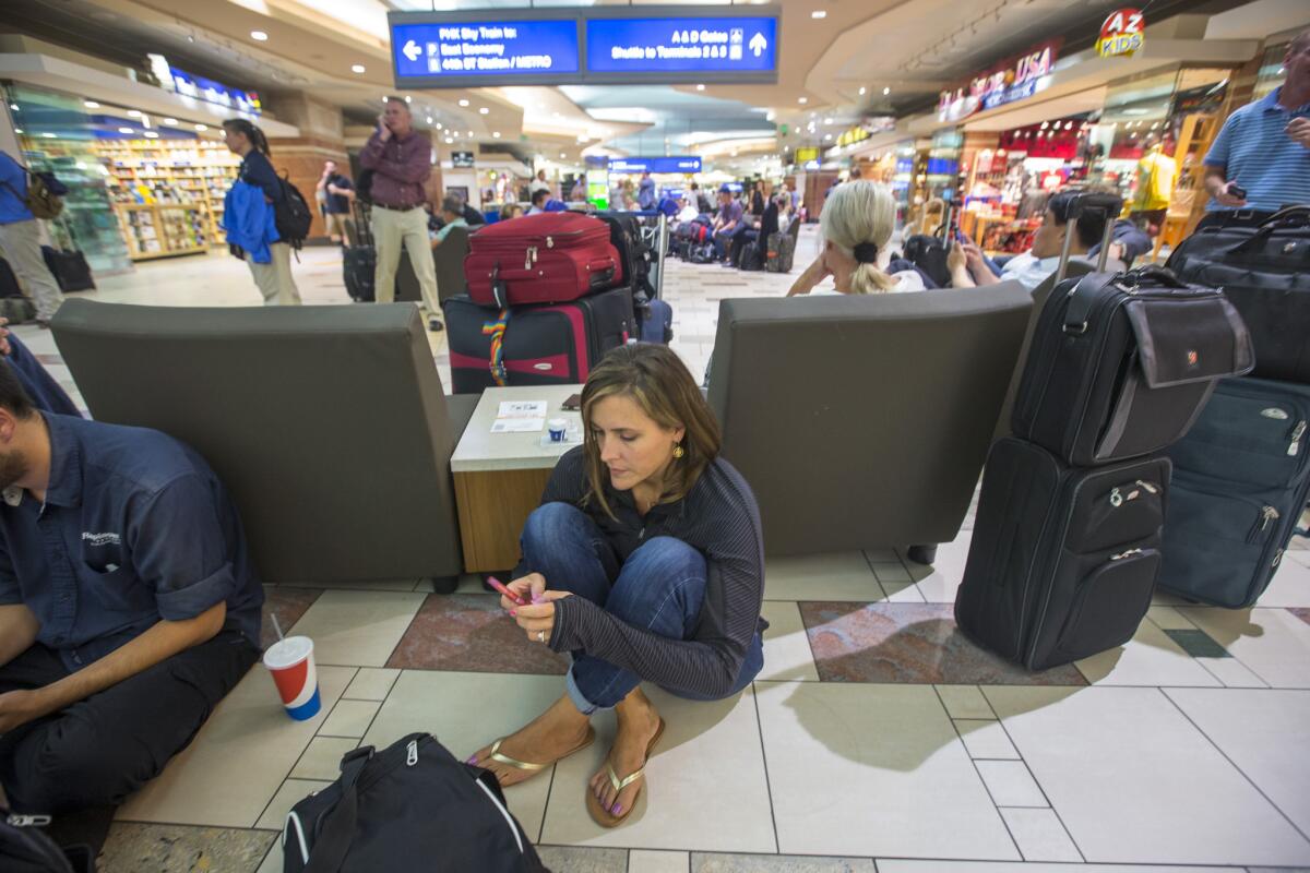 Travelers wait in Terminal 4 at Phoenix Sky Harbor International Airport after police closed it while hunting for a shooting suspect, who was later arrested.