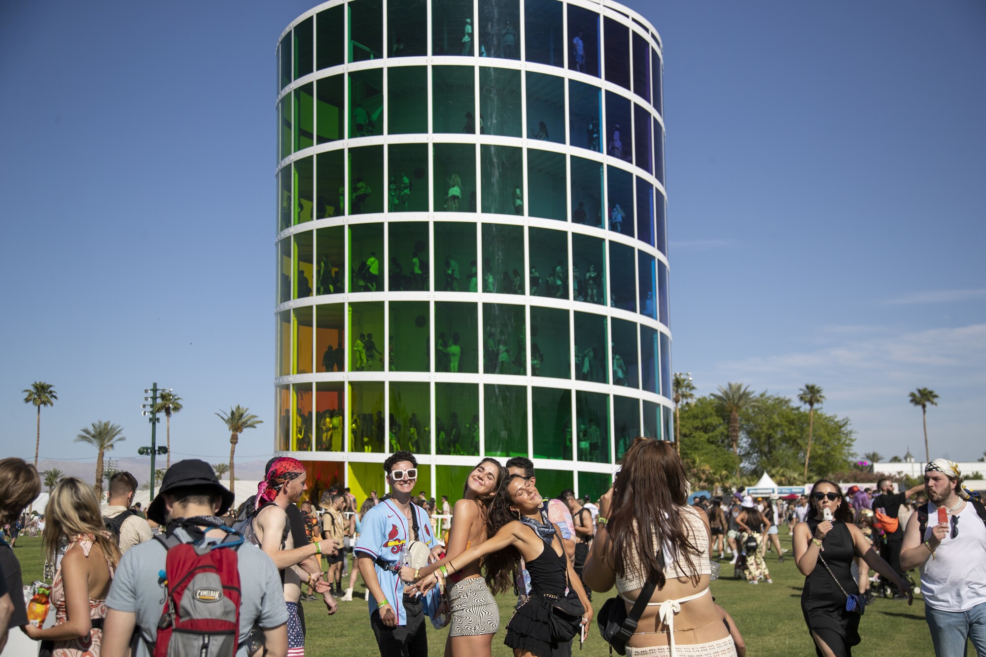 Festival goers pose for photos in front of a multilevel building in which people are walking.