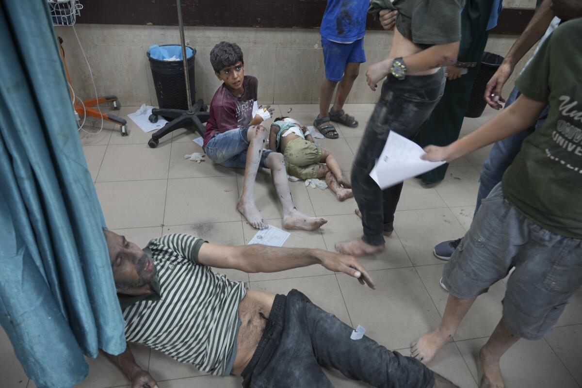 Palestinos heridos por bombardeos israelíes contra la Franja de Gaza sentados en el piso del hospital Al-Aqsa, 