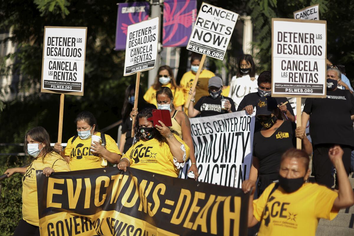 Protesters carry signs and banners with messages including "Evictions = Death" and "Cancel the rents now"