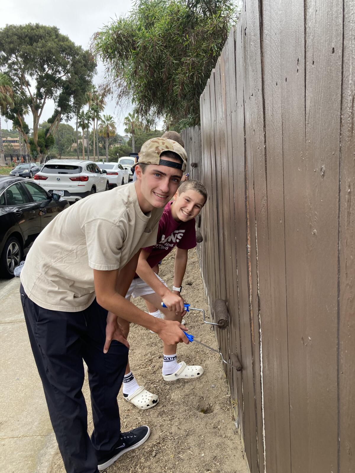 Freshman Dax Labrum paints Molavista’s fence alongside his teammates.