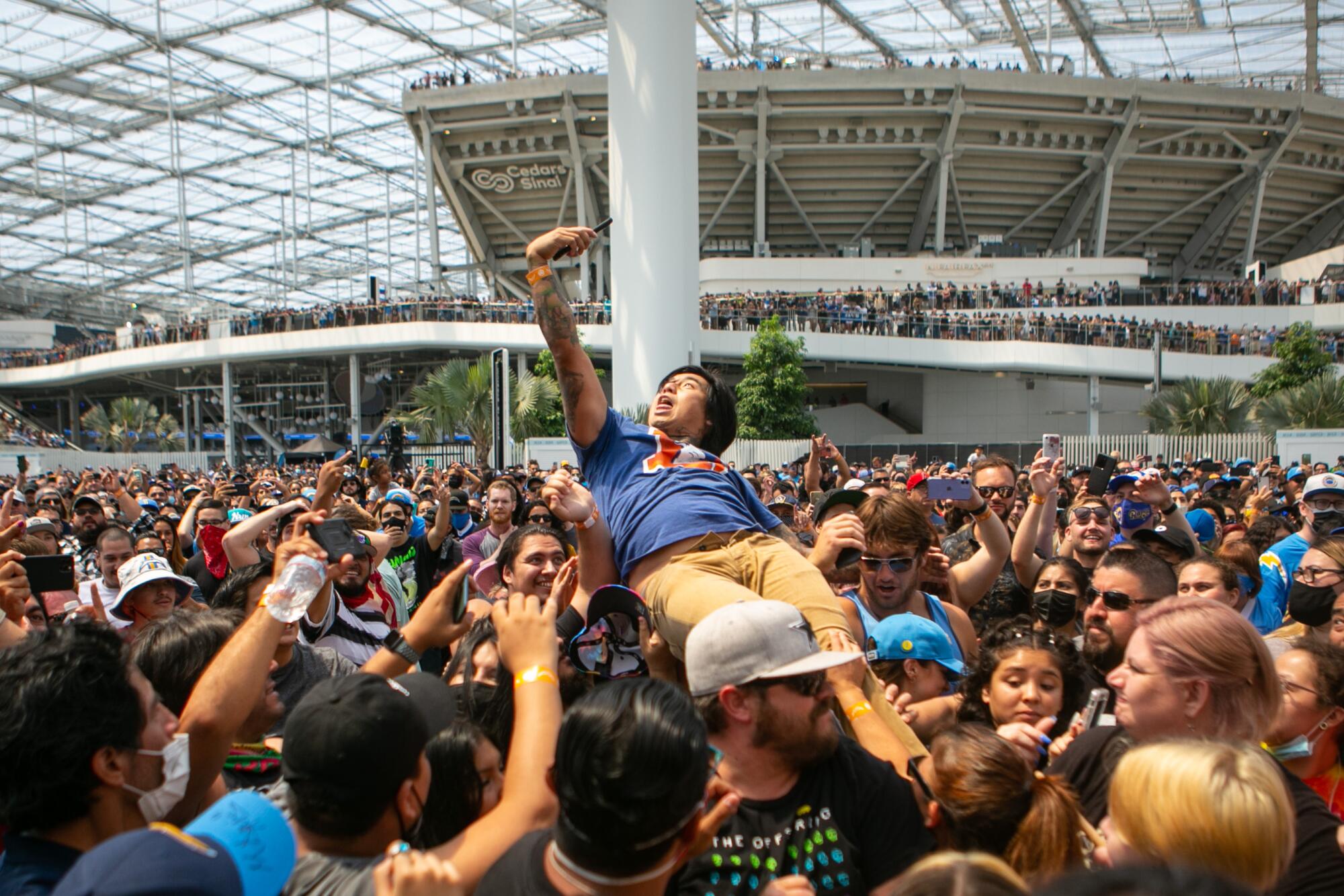 A spectator crowd surfs during a performance by The Offspring at the Charger Fan Fest on Sunday at SoFi Stadium.