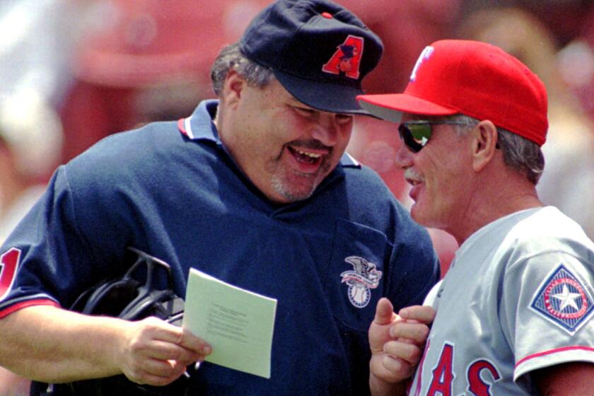 FILE - In this June 8, 1997, file photo, home plate umpire Ken Kaiser, left, and Texas Rangers manager Johnny Oates go over the lineup before a baseball game against the Kansas City Royals in Kansas City, Mo. Kaiser, a former major league umpire, died in his hometown of Rochester, N.Y., on Tuesday, Aug. 8, the World Umpires Association said Thursday, Aug. 10, 2017. He was 72. Kaiser was a colorful figure in more than two decades on the diamond. His career abruptly ended nearly two decades ago during labor talks. He joined a group of umpires who submitted resignations in 1999 during negotiations. The gamble by the Major League Umpires Association failed and he was not rehired. (AP Photo/Orlin Wagner, File)