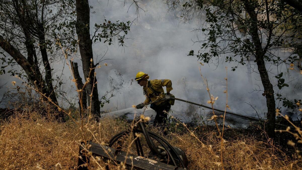 A firefighter from Los Angeles helps to douse hot spots near homes in Redding, Calif.