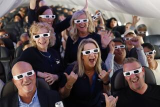 April 8: Wearing solar eclipse glasses, the flight crew, including Chirstina Venegas of San Diego, center, take a photo with passengers on an Alaska Airlines flight from San Diego to Washington Dulles International Airport on Monday, April 8, 2024. The passengers and crew saw the eclipse in its totality during the flight over Missouri. (K.C. Alfred / The San Diego Union-Tribune)